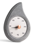 angled view of stone teardrop shaped sauna thermometer with a brass knob on a white background