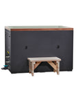 Green cuboid cold plunge tub seen from the front, cedar step alongside and fill valves visible