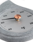 close up angle of stone teardrop shaped sauna thermometer with a brass knob on a white background
