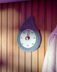 stone teardrop shaped sauna thermometer with a brass knob hanging on a wooden wall with a robe on a hook