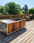 Outdoor hot tub or plunge tub on a wooden deck with trees in the background and a woman sitting on a bench nearby.