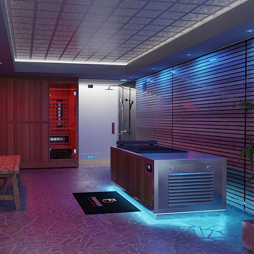 A modern indoor spa or wellness room featuring a large stainless steel cold plunge tub and wood sauna/steam unit, a glass shower enclosure, a red sauna compartment, patterned flooring, and ambient blue and purple lighting.