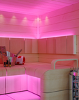 Harvia Cilindro Sauna Heater sauna interior with pink accent lighting with 2 bench levels and bucket with folded towel and oils