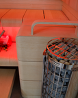 Harvia Cilindro Sauna Heater sauna interior close up heater filled with stones with 2 bench levels and bucket with folded towel