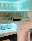 Harvia The Wall Sauna Heater Stainless Steel mounted on sauna wall full view with stones underneath stainless steel grate sauna interior with light blue indirect LED lighting