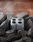 sauna steam stone with four holes surrounded by larger stones on a wooden surface