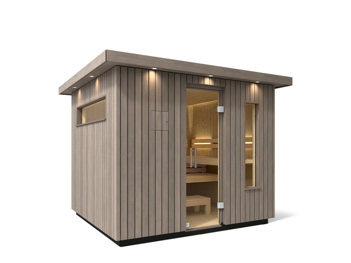 Kohler C2 Sauna Weathered Spruce exterior angled view with indirect lighting on the eaves and a clear glass door