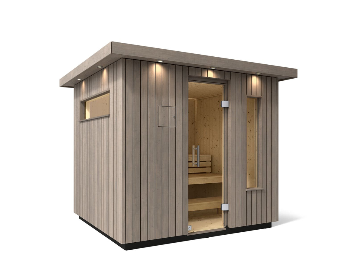 Kohler C2 Sauna Weathered Spruce exterior angled view with indirect lighting on the eaves and a clear glass door