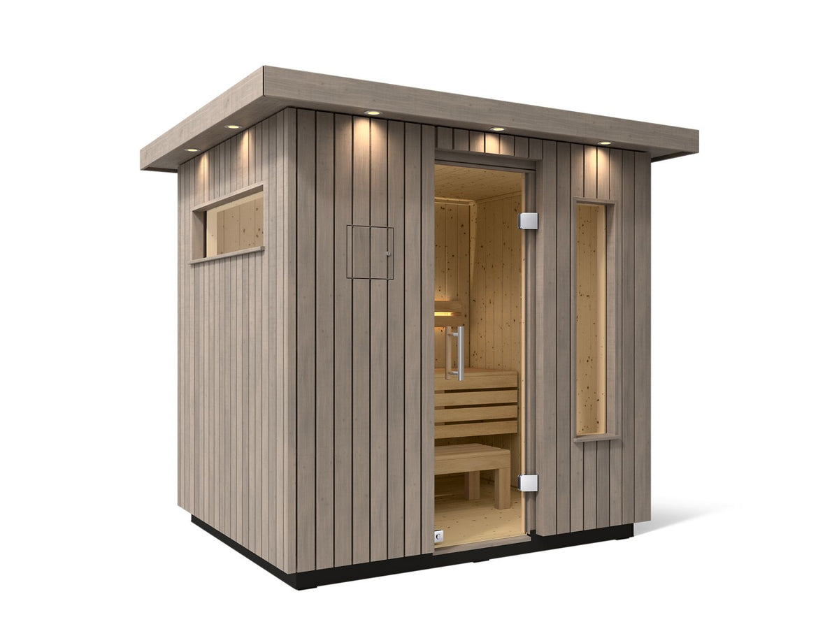Kohler C2 Sauna Weathered Spruce exterior angled view with indirect lighting on the eaves and a clear glass door