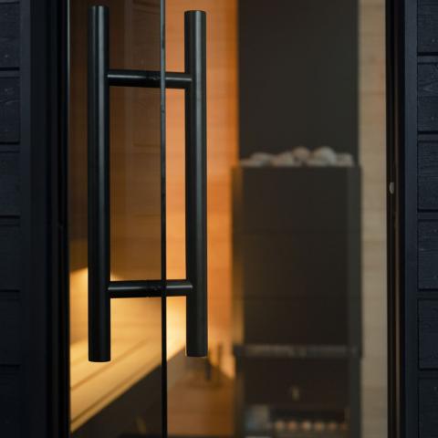 Close-up of a black door handle on a glass door with a blurred interior background