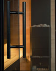 Close-up of a black door handle on a glass door with a blurred interior background