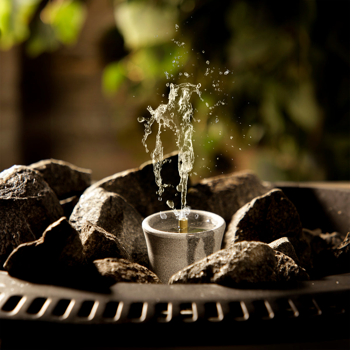 grey sauna stone diffuser amongst dark grey heater stones with a blurred natural background