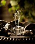 grey sauna stone diffuser amongst dark grey heater stones with a blurred natural background