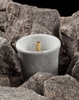 grey sauna stone with a cylindrical hole in a pile of heater stones