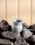 light grey sauna stone sitting amongst dark grey heater stones against a wood background