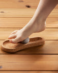 Person stepping onto a cork footrest with a sauna stone on a wooden floor