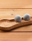Cork tray with two gray spherical objects on a wooden surface