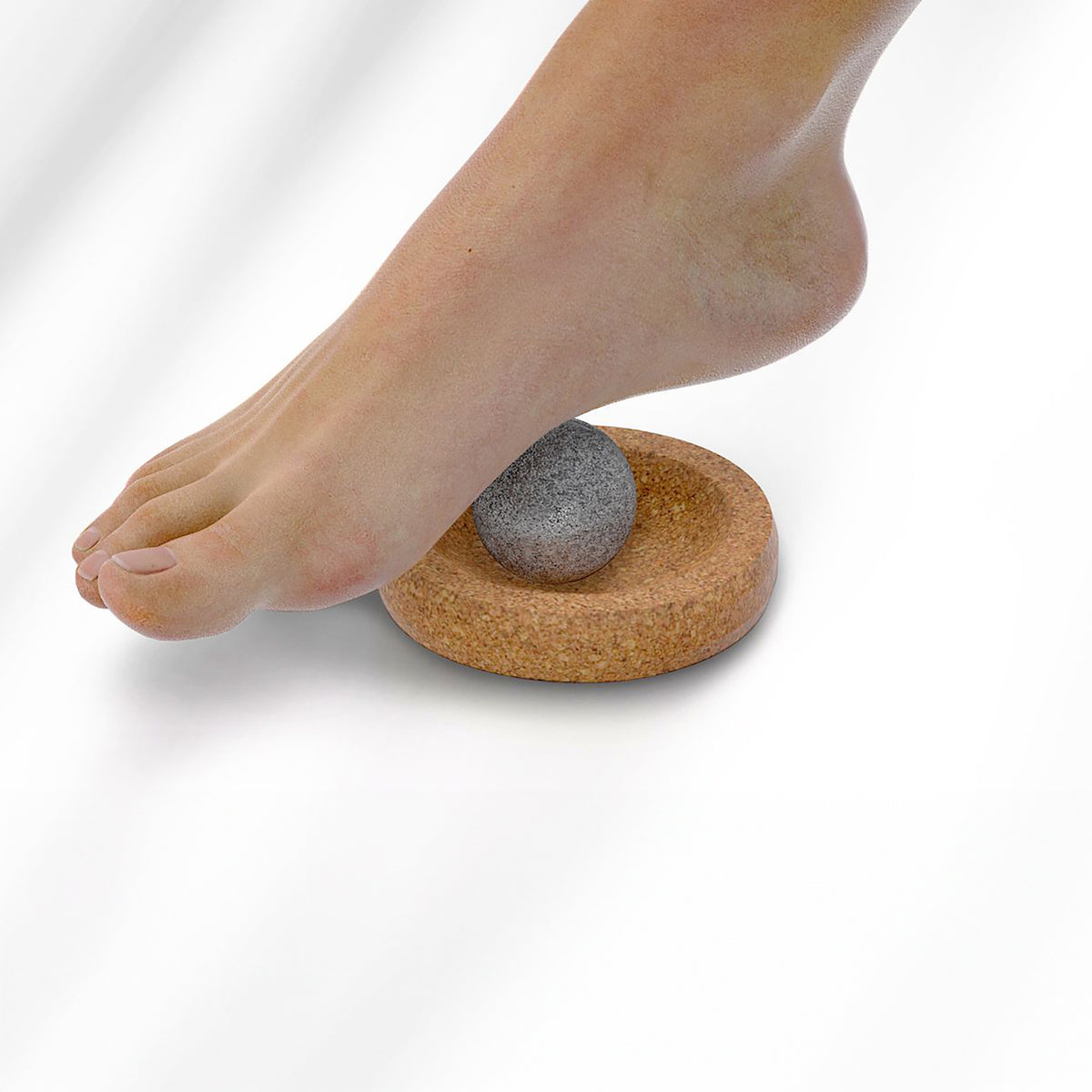 Foot pressing a stone on a cork base against a white background