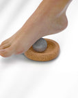 Foot pressing a stone on a cork base against a white background