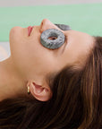 Woman receiving a stone facial treatment with a green background