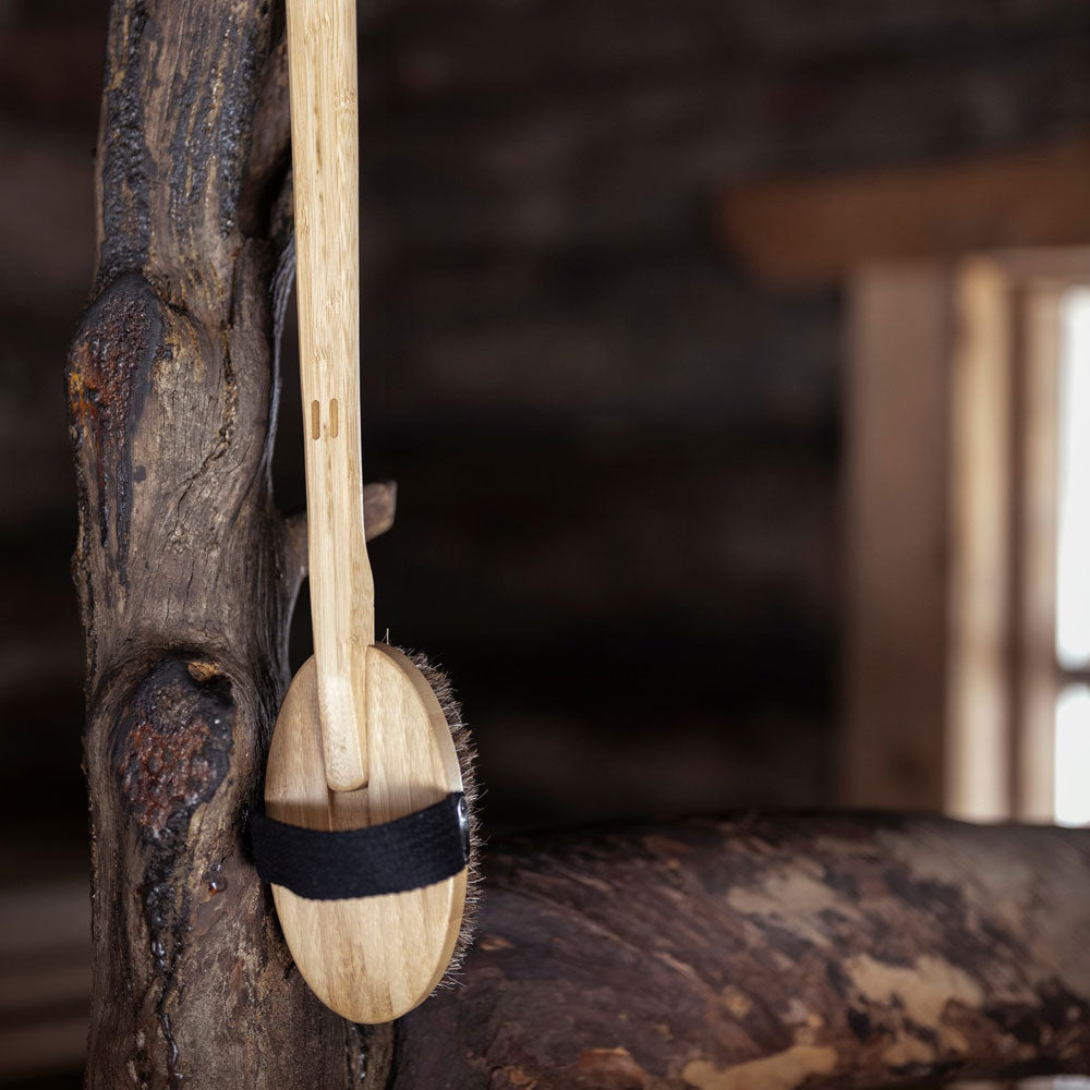Wooden brush with a black band hanging on a wooden surface
