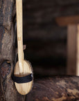 Wooden brush with a black band hanging on a wooden surface