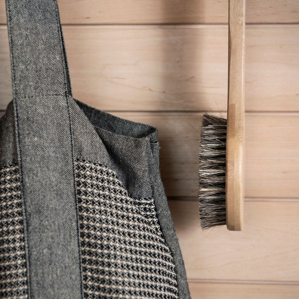 Gray textured bag with a patterned strap against a wooden background