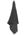 dark grey textured towel hanging on a white background
